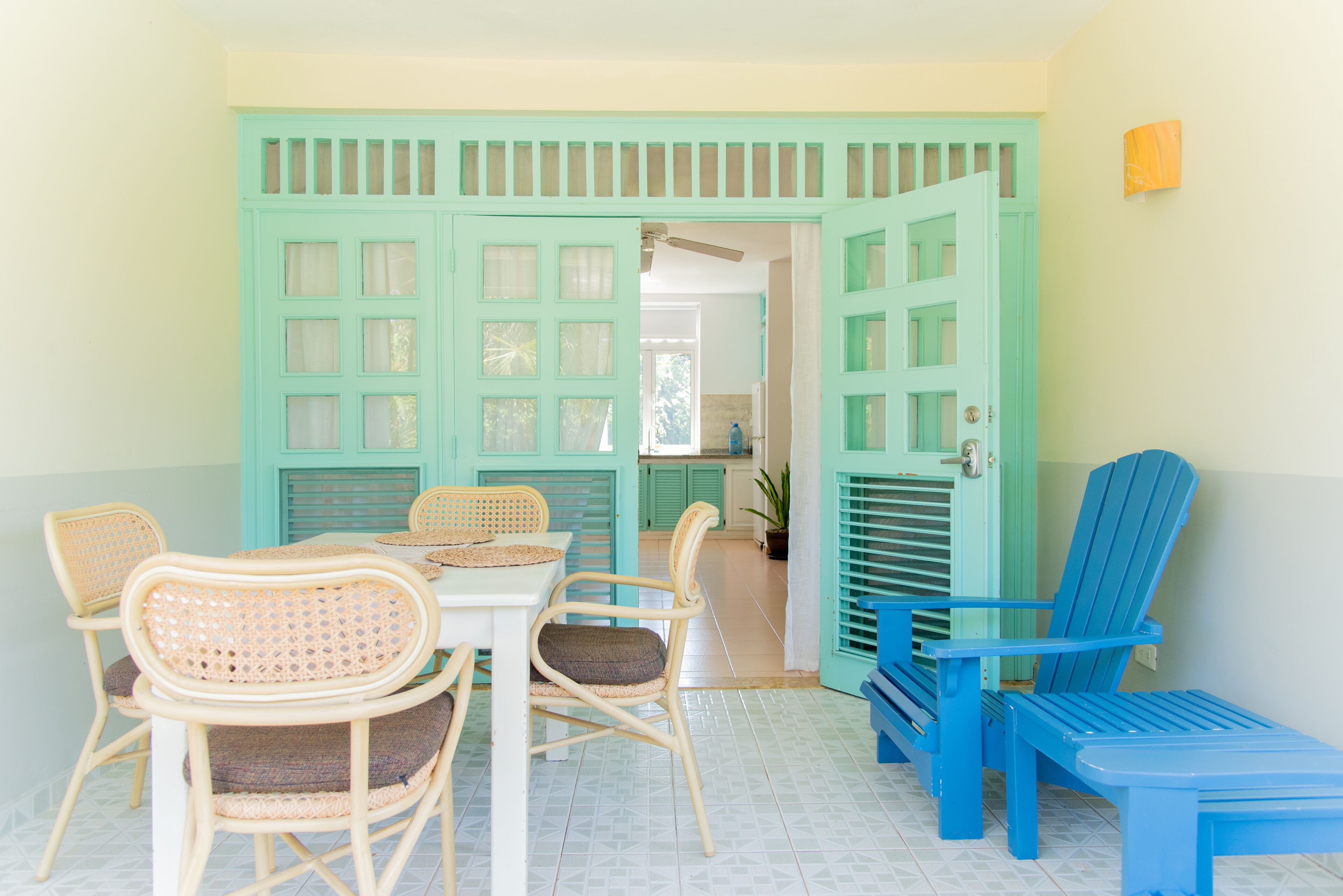 Un coin repas avec une table et des chaises, une chaise bleue et une porte de couleur turquoise.