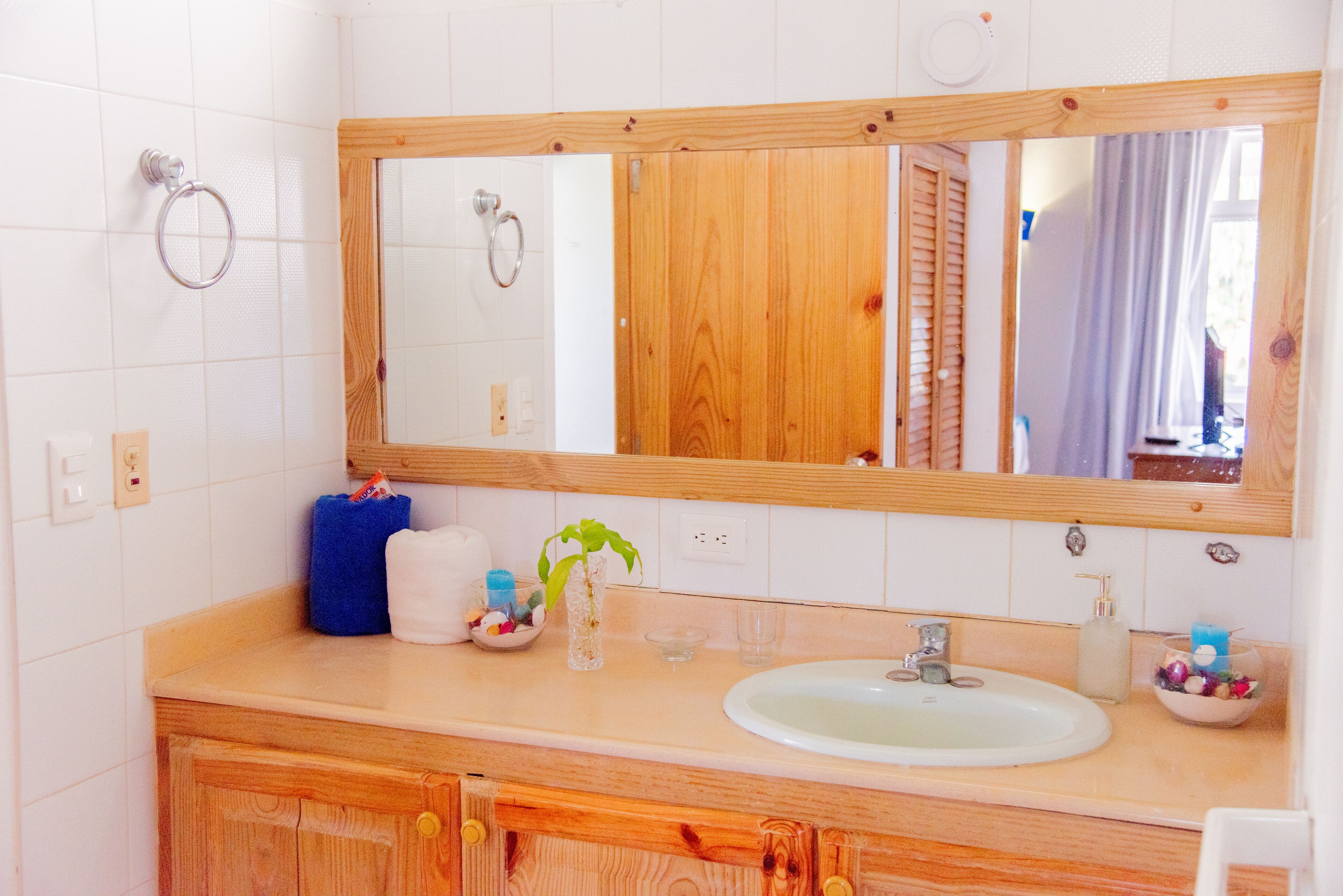 A bathroom with a wooden vanity, a large mirror, a sink, and a towel rack.