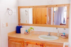A bathroom with a wooden vanity, a large mirror, a sink, and a towel rack.