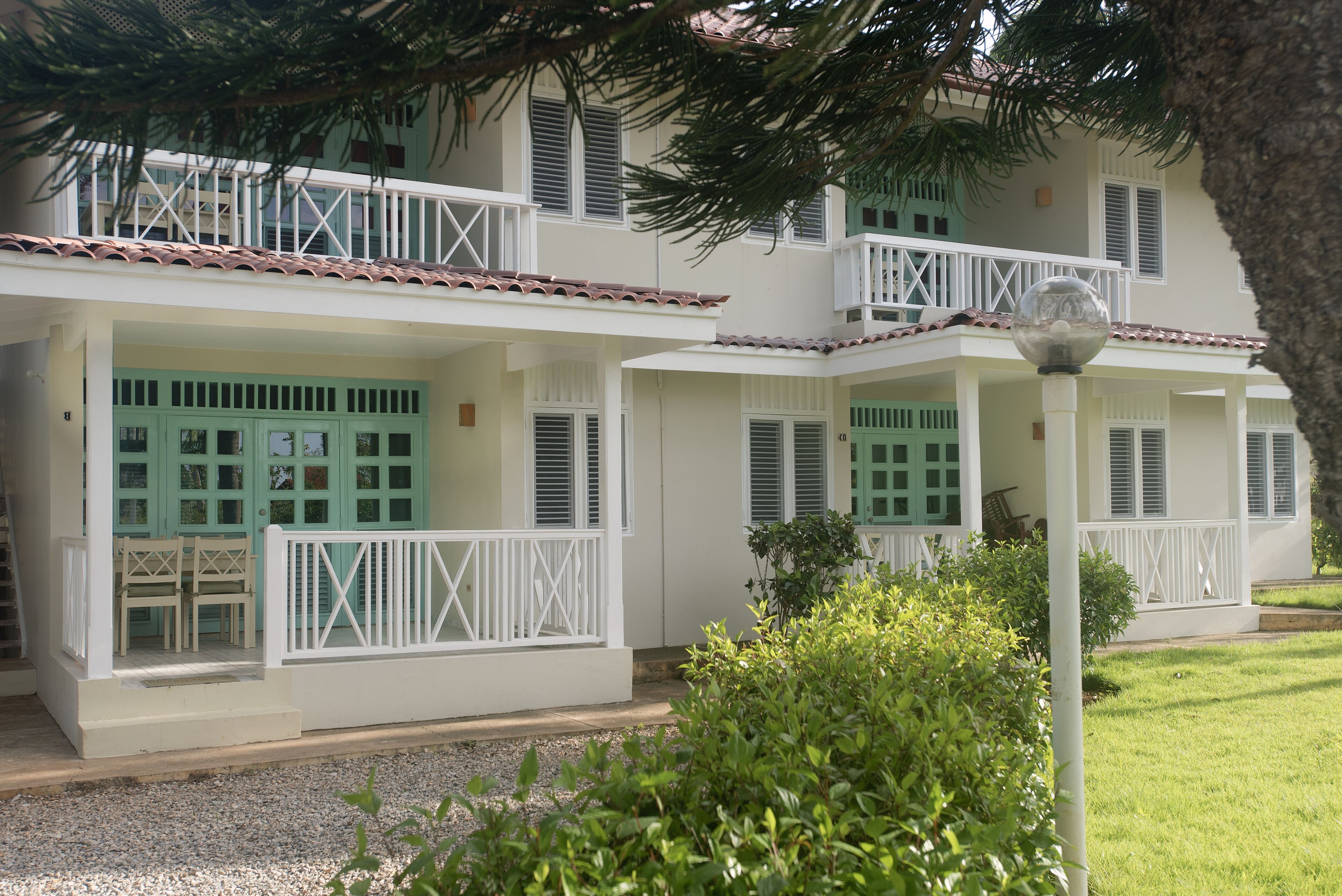 Un edificio a due piani con un balcone, un portico coperto e un piccolo giardino.