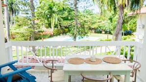 Un espace extérieur aménagé, abrité et doté d’une table et de chaises, donnant sur un jardin avec une piscine.