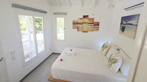 Une chambre à coucher avec un lit, une œuvre d’art accrochée au mur et une porte donnant sur un balcon.