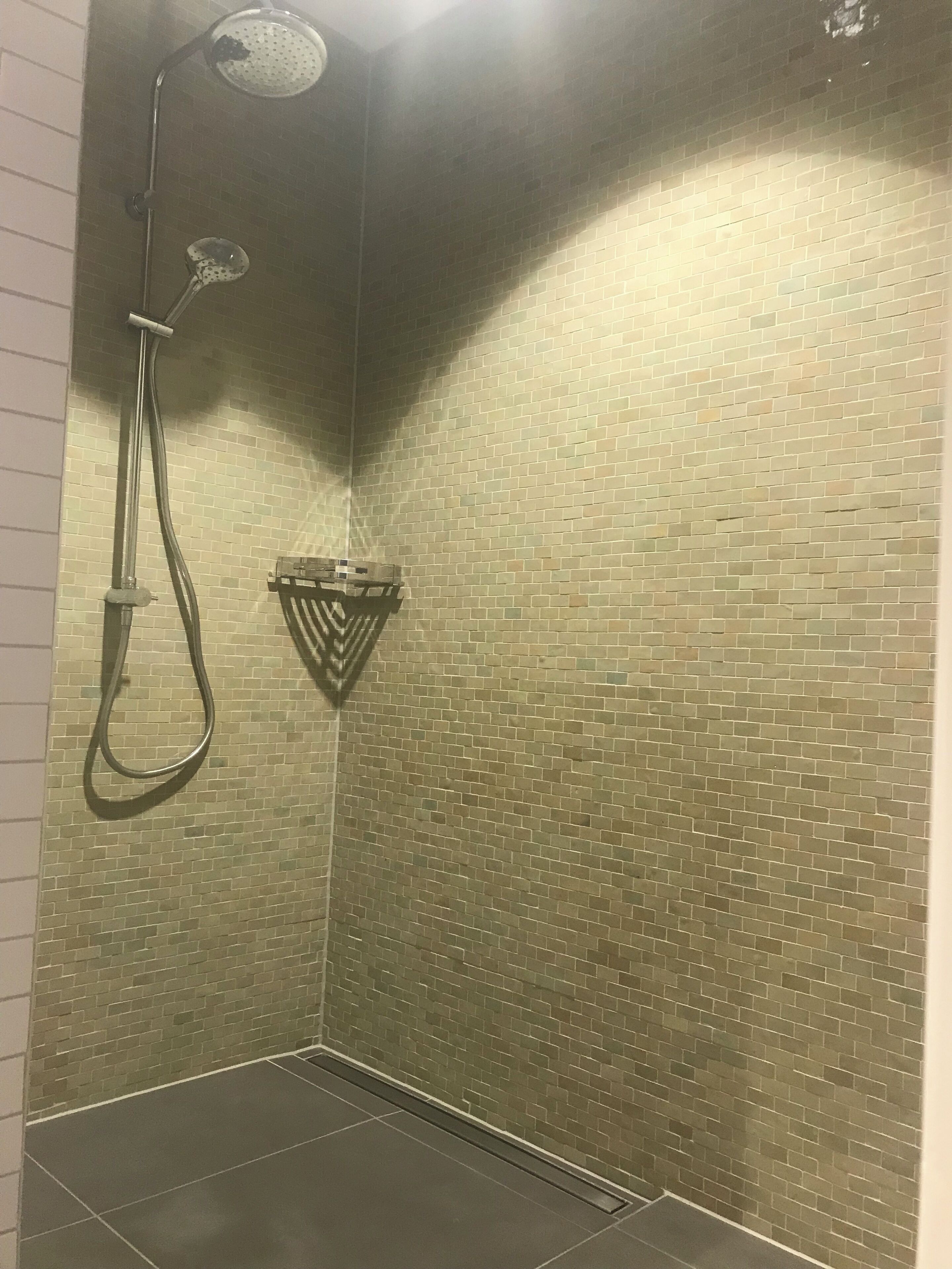 Zona de ducha con pared de azulejos y ducha.