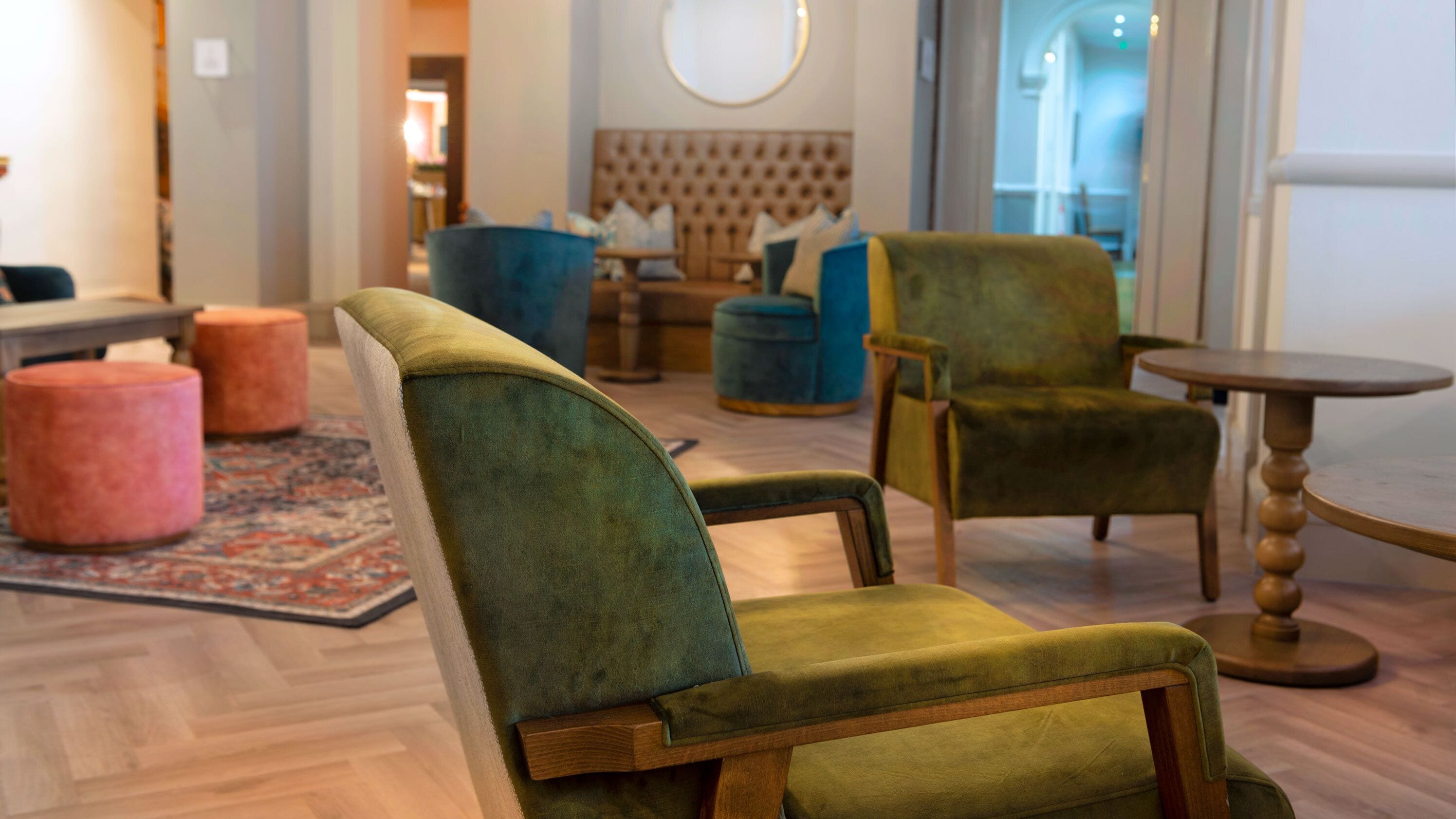 A room with a green upholstered armchair, a blue armchair, and a wooden table.