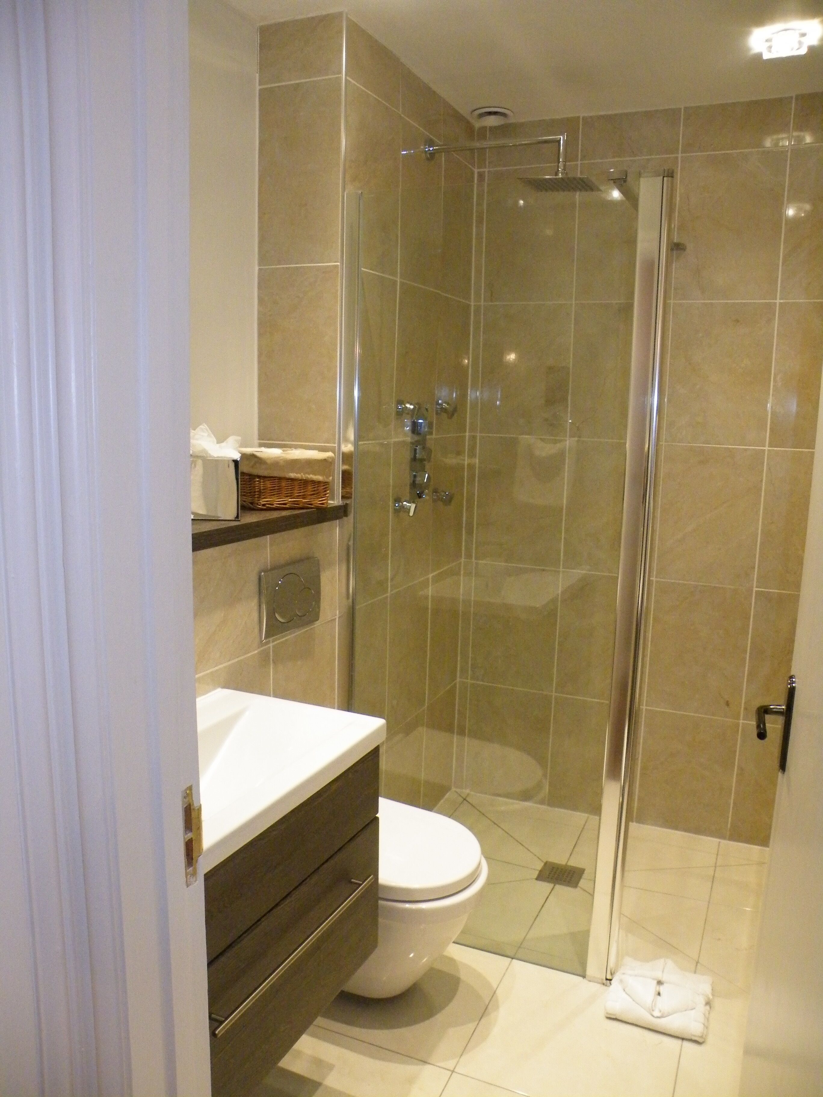 A modern bathroom with a glass-enclosed shower, a white toilet, and a vanity with a mirror.