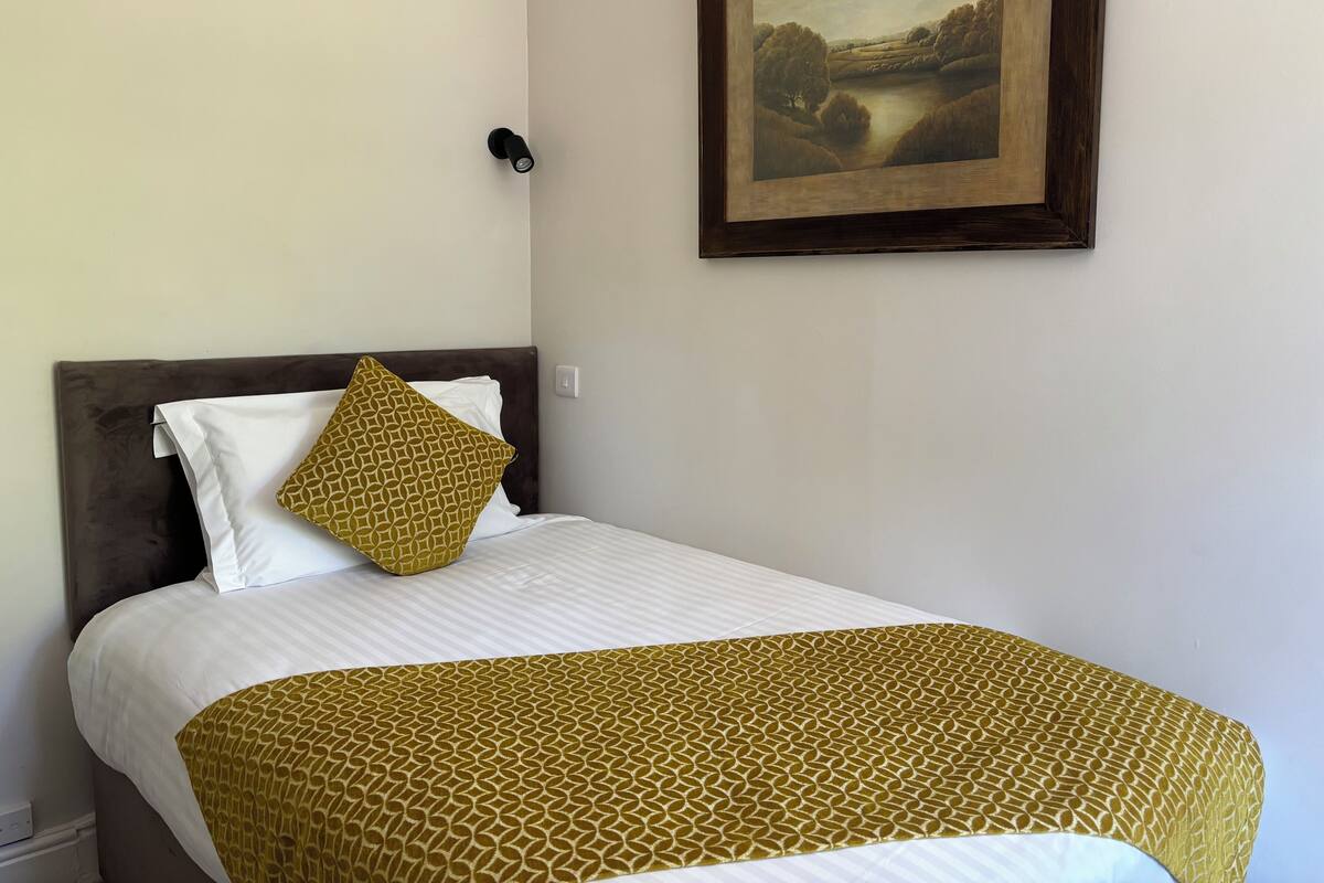 A neatly made bed with a patterned bedspread and a single decorative pillow.