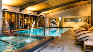 A pool area with a hot tub, lounge chairs, and a stone wall. - Hatherley Manor Hotel & Spa (Gloucester)