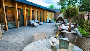 Un patio al aire libre con sillones de descanso, una mesa con champán y un cartel de spa.