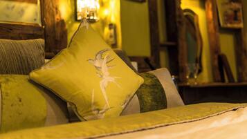 A cozy room with a bed, a green pillow with a bird design, and a lamp.