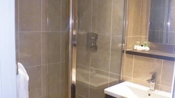 A modern bathroom with a glass-enclosed shower, a sink with a mirror above it, and a towel hanging on the wall.