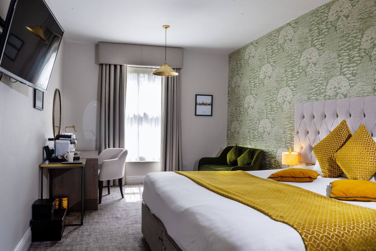 A hotel room with a bed, a desk, a chair, a television, and a window with curtains.