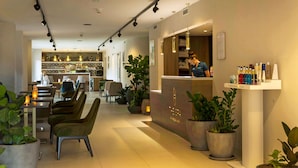 Un café moderno con barra, asientos y plantas en macetas.