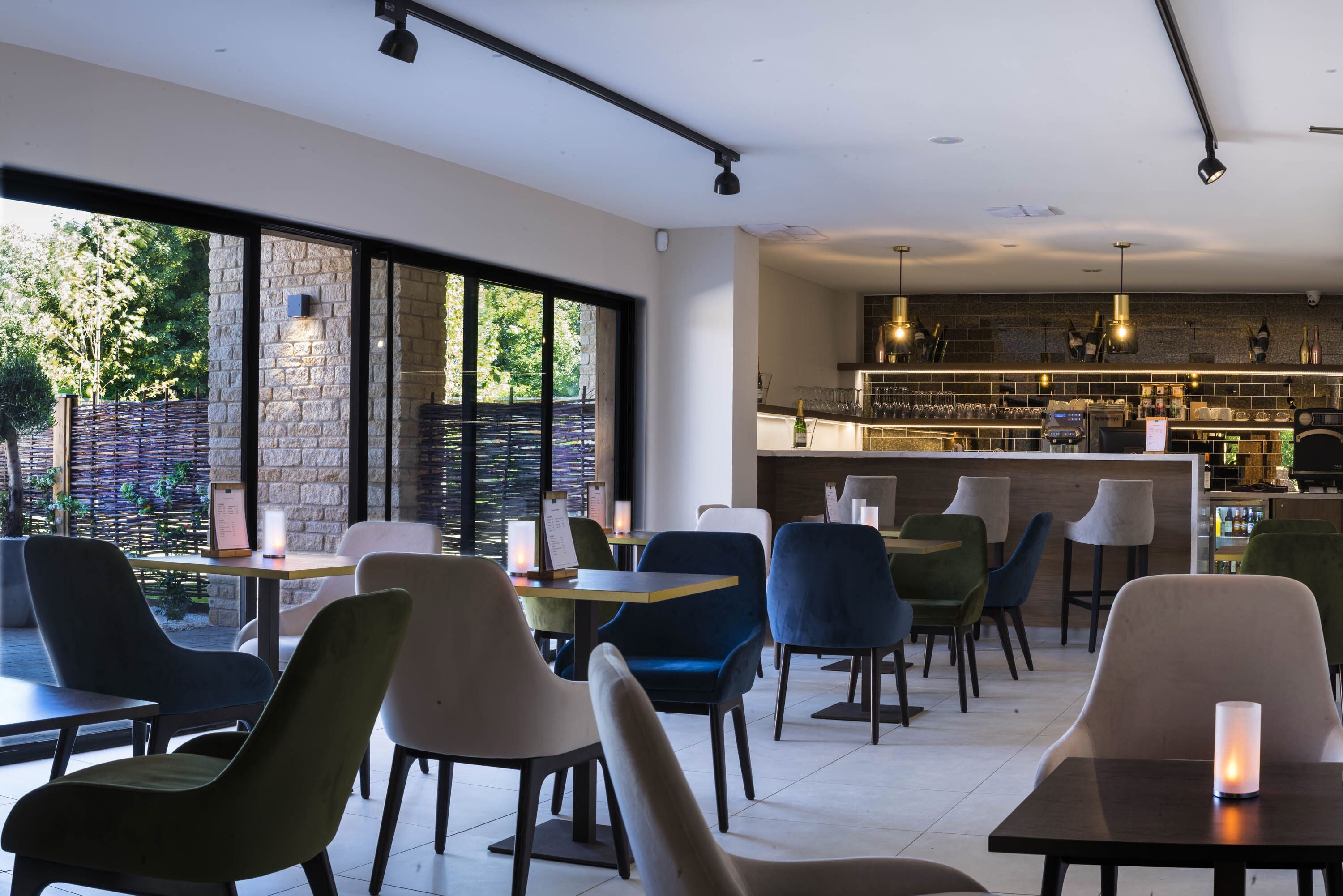 En modern restaurang med en bardel, stora fönster och en variation av sittplatser.