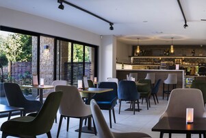 Un restaurante moderno con barra, ventanas amplias y diferentes opciones de asientos.