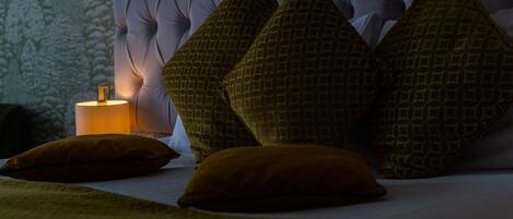 A bed with a tufted headboard, multiple pillows, and a bedside lamp.
