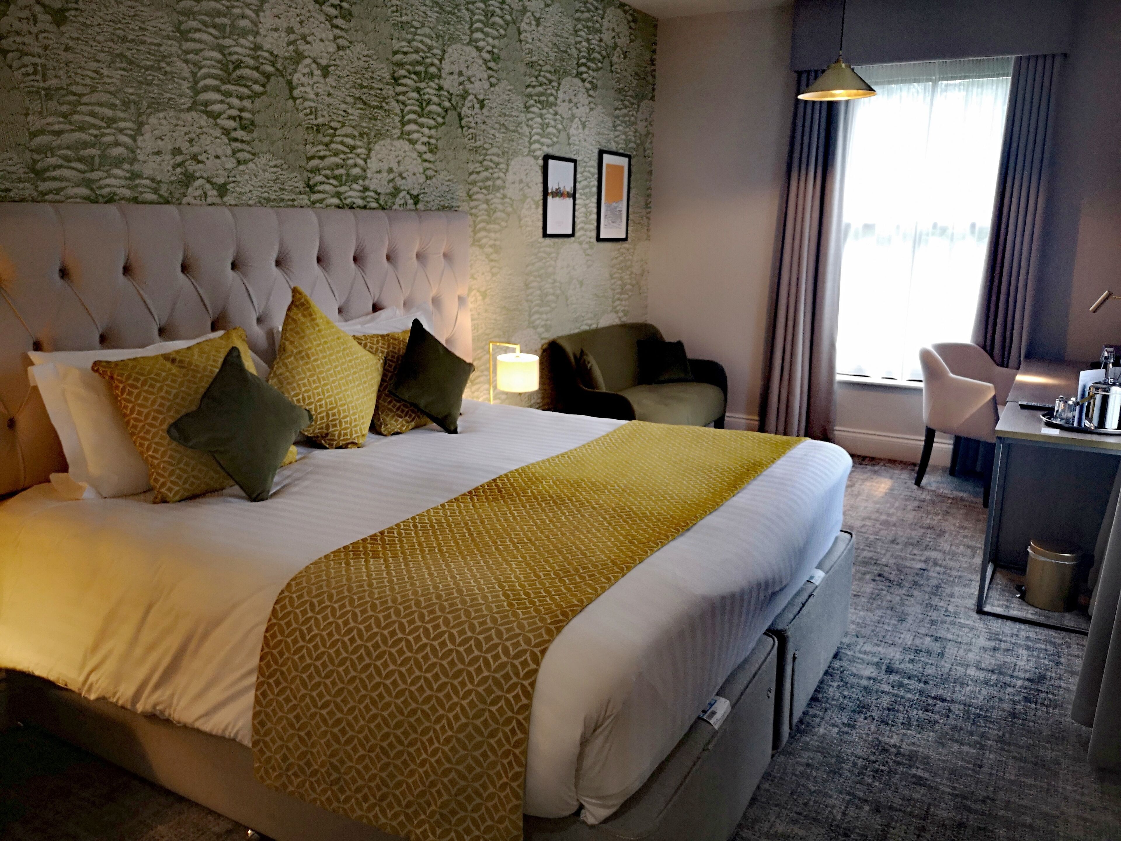 Una habitación de hotel con una cama grande, un escritorio, una silla y una lámpara.