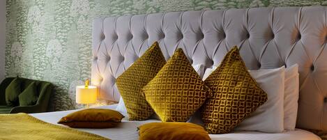 A neatly made bed with a tufted headboard, multiple pillows, and a bedside lamp.