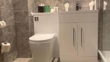 Ein modernes Badezimmer mit Toilette, Waschbecken mit Spiegel und Pflegeprodukten auf der Ablagefläche.