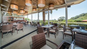 Un vaste espace extérieur aménagé pour les repas, avec des meubles en osier et une vue sur les collines.