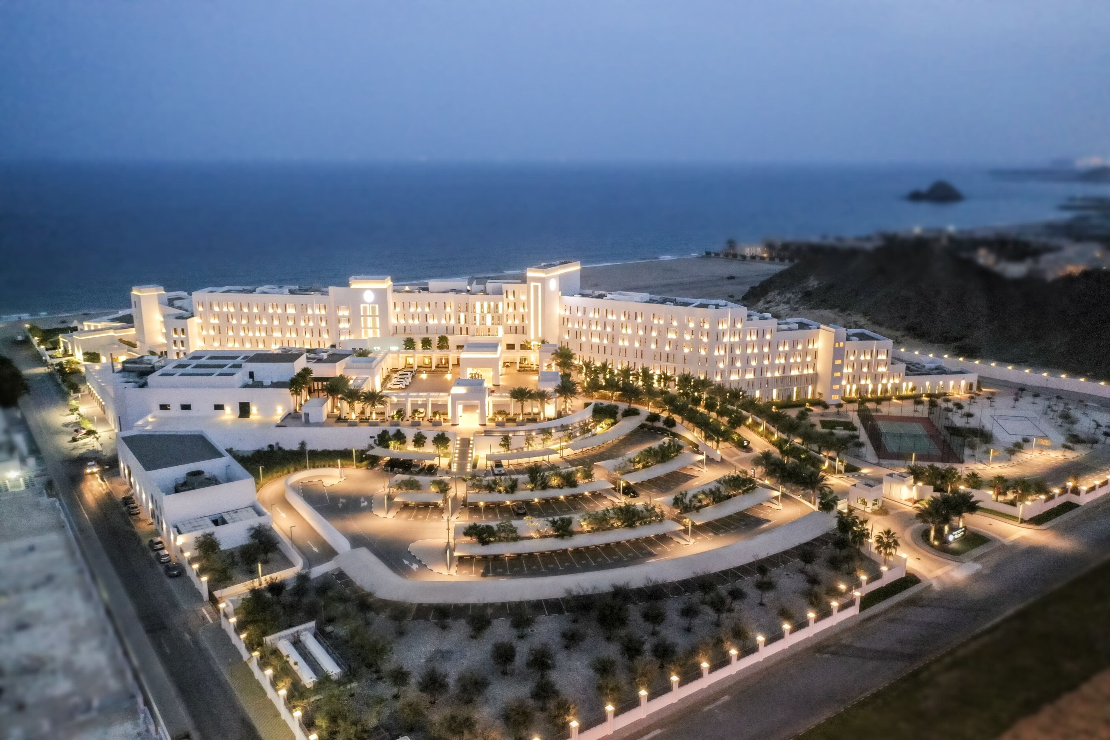 Un hotel grande con varias secciones, un patio central y vista al océano.