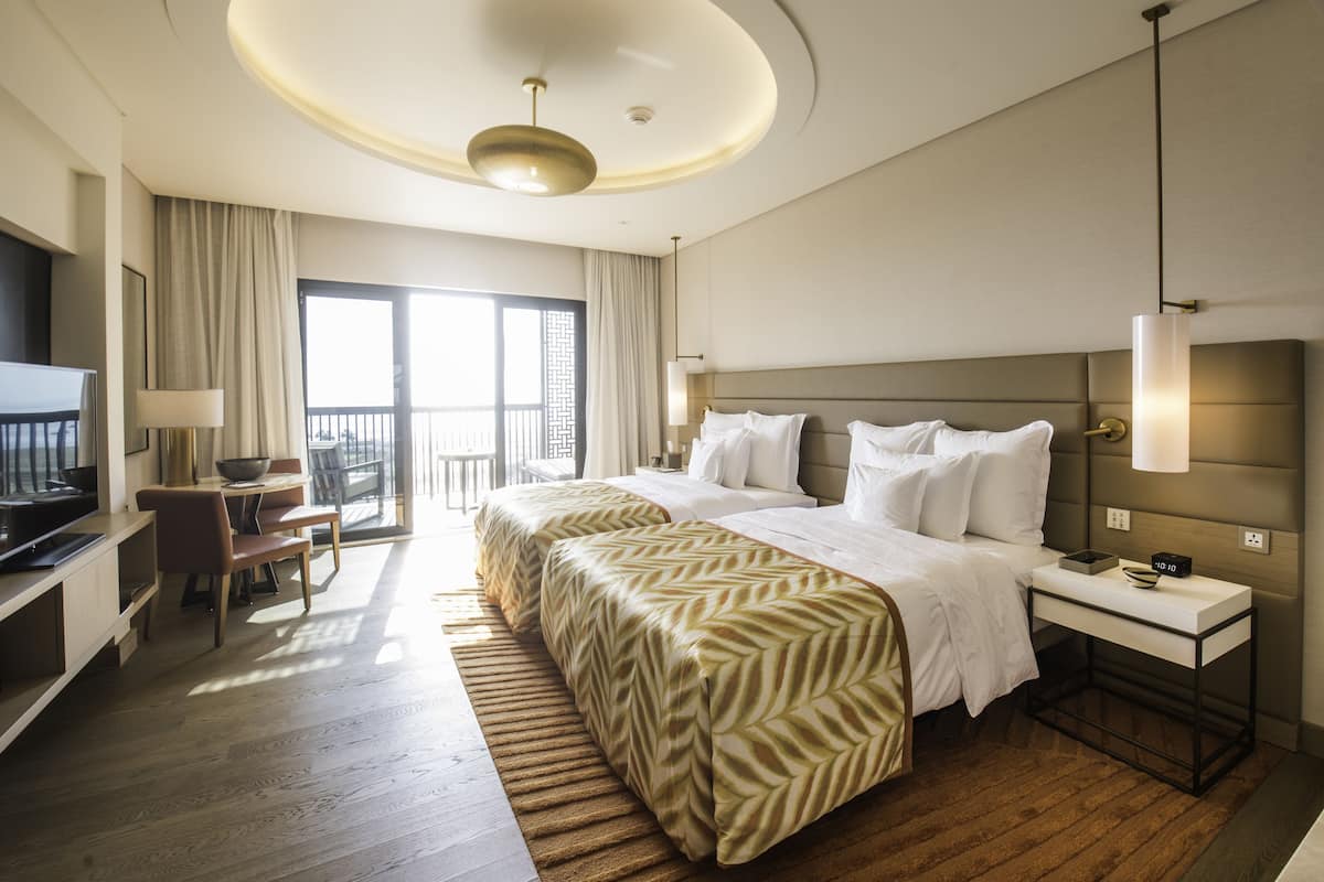 Habitación de hotel con una cama grande, un escritorio, una silla y un televisor.