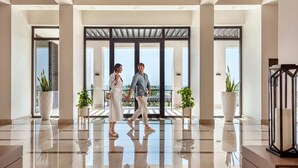 A modern hotel lobby with a reflective floor, large windows, and potted plants. - InterContinental Fujairah Resort by IHG (Al Aqah)