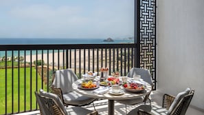 A balcony with a table set for breakfast, overlooking a beach and golf course.