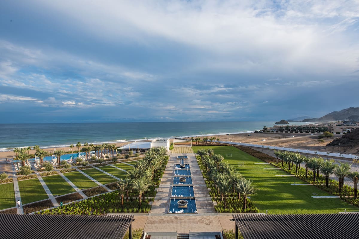 Un resort con piscina, palmeras y vista a la playa y al océano.