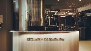 A reception desk with 'ESTALAGEM DE SANTA IRA' signage, a modern chandelier, and a large metallic structure in the background. - Estalagem De Santa Iria (Tomar)