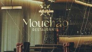 A restaurant interior with a modern design, featuring a black marble countertop, wooden shelves, and a decorative ceiling with green plants. - Estalagem De Santa Iria (Tomar)