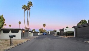 A street view of a residential area with single-story houses, a clear sky, and a parked car. - La Vida Local By Signature Vacation Rentals (Tucson)
