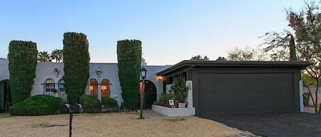 A residential property with a garage, a landscaped front yard, and a building with a stone facade.