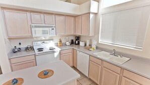 A modern kitchen with light wood cabinets, a white countertop, a built-in microwave, a stove, a dishwasher, and a window with blinds. - Keep It Simple By Signature Vacation Rentals (Glendale)