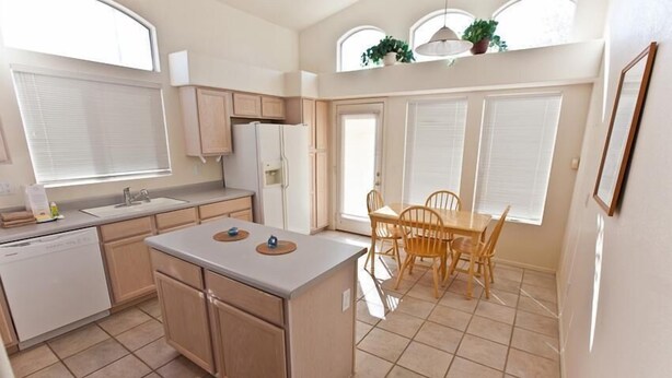 A kitchen with a central island, wooden cabinets, a dishwasher, and a dining area with a table and chairs. - Keep It Simple By Signature Vacation Rentals (Glendale)