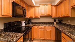 A kitchen with wooden cabinets, granite countertops, a black stove, a microwave, and a coffee maker. - Just Darling By Signature Vacation Rentals (Phoenix)