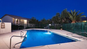 A rectangular swimming pool with a metal railing, surrounded by a green fence, and a house in the background. - Just Darling By Signature Vacation Rentals (Phoenix)