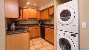 A compact kitchen with wooden cabinets, a built-in dishwasher, and a stacked washer and dryer. - Just Darling By Signature Vacation Rentals (Phoenix)