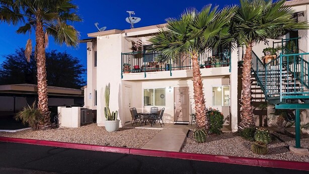 A two-story building with a balcony, a patio with a table and chairs, and several palm trees. - Just Darling By Signature Vacation Rentals (Phoenix)