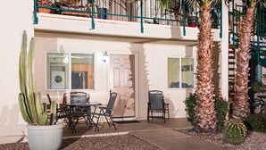 A patio area with a table and chairs, a potted cactus, and a palm tree. - Just Darling By Signature Vacation Rentals (Phoenix)