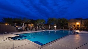 A rectangular pool with a tiled deck, lounge chairs, and a covered seating area with pillars. - Hot Spot at Desert Ridge By Signature Vacation R (Phoenix)