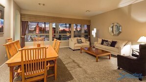 A living room with a dining table, two sofas, a coffee table, and a large window with a view. - Hole in One By Signature Vacation Rentals (Goodyear)