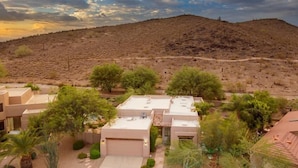 Una zona residencial con varias casas, un camino de entrada pavimentado y un paisaje montañoso al fondo.