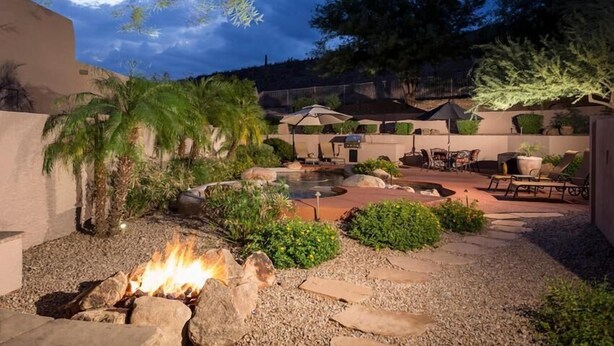 Un patio con un brasero, mobiliario exterior y una piscina.