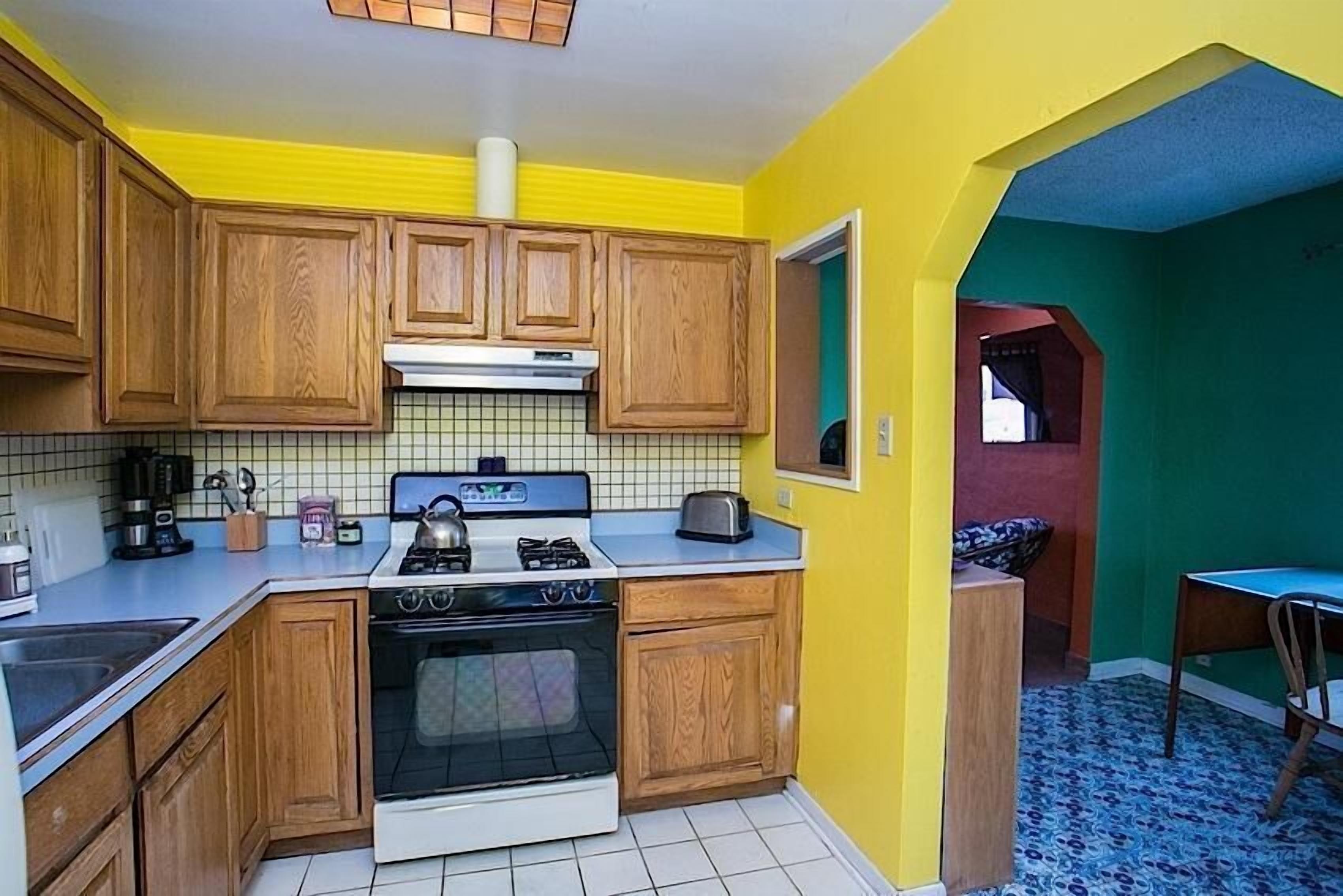 A kitchen with wooden cabinets, a stove, and a tiled backsplash.