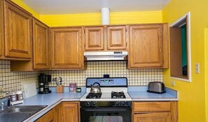 Eine Küche mit Holzausstattung, einem Gasherd, einer Mikrowelle und einem Toaster.