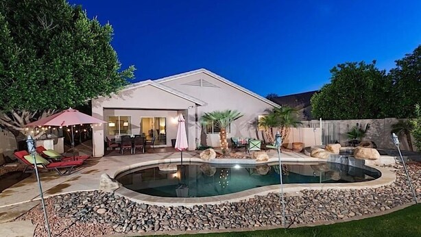 Una casa con piscina, muebles de jardín y un espacio exterior cubierto.