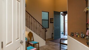 A staircase with a wooden handrail and a chair with a striped cushion at the bottom. - Heart of Tucson By Signature Vacation Rentals (Tucson)