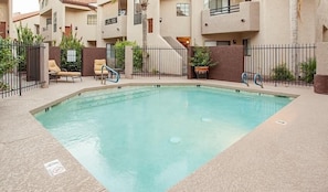 A rectangular pool with a clear blue water, surrounded by a low fence and lounge chairs. - Happy Ours By Signature Vacation Rentals (Paradise Valley)