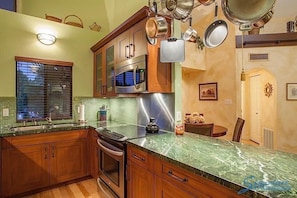 A kitchen with wooden cabinets, a stainless steel oven, and a granite countertop. - Happy Ours By Signature Vacation Rentals (Paradise Valley)