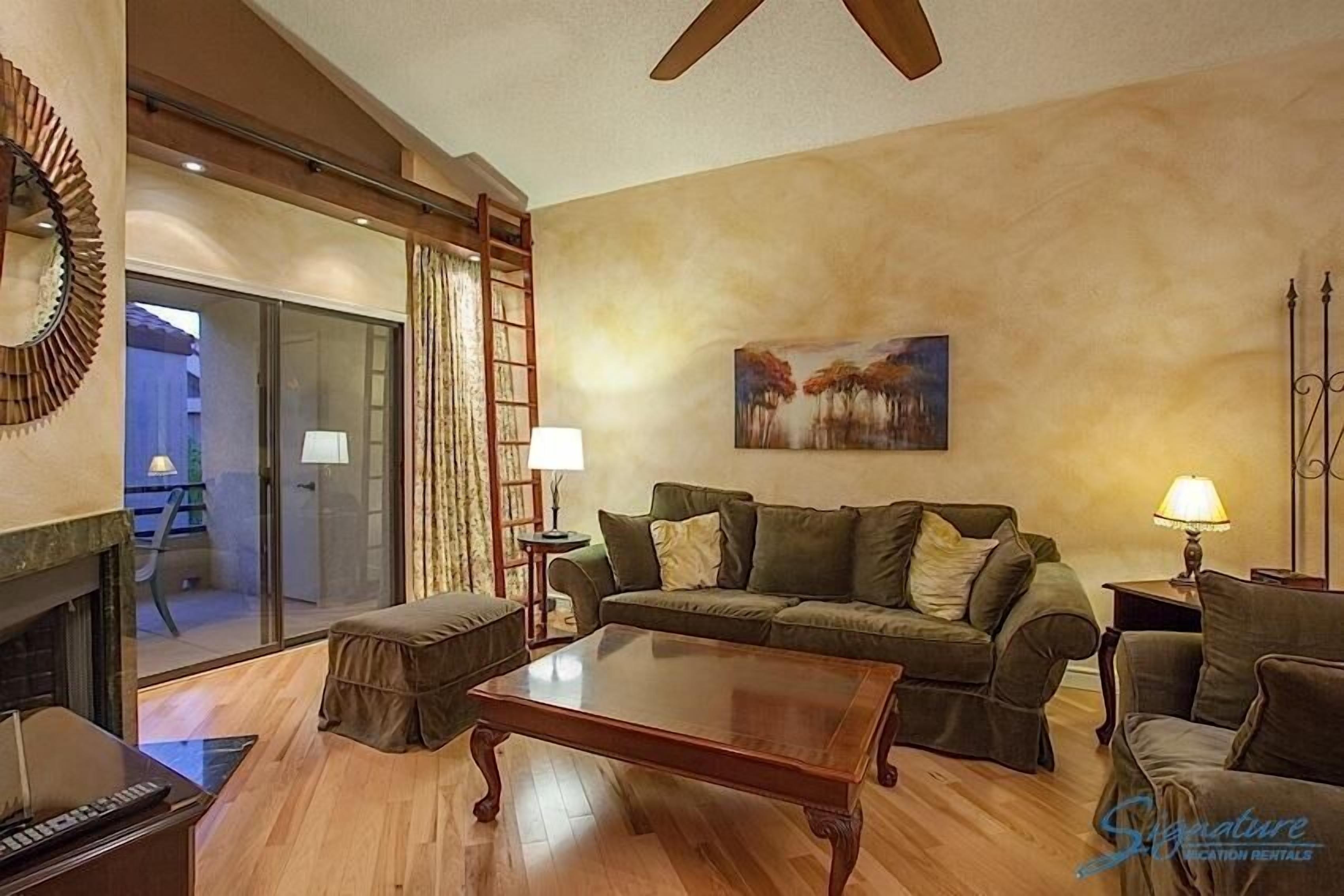 A living room with a sofa set, a coffee table, a fireplace, and a painting on the wall.
